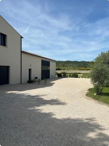 a large white building with a driveway next to it at Appartement neuf Bédoin - Les Cinglés du Mont Ventoux in Mormoiron