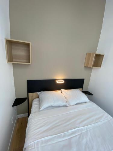 - une chambre avec un lit blanc et une tête de lit noire dans l'établissement Appartement Bonne Nouvelle, à Paris