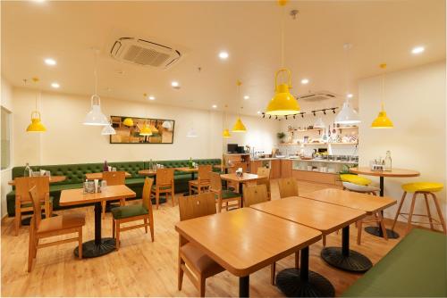 un restaurante con mesas de madera y sillas verdes en Bloom Hotel - Medicity Gurugram, Near Medanta Hospital en Gurgaon
