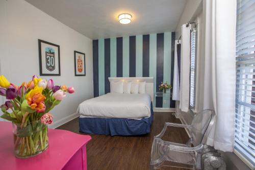 Edwardian Hotel في سان فرانسيسكو: غرفة في الفندق بها سرير و مزهرية من الزهور