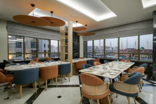 Un restaurante con mesas y sillas y grandes ventanales. en Rotana Al Manakha Madinah, en Medina