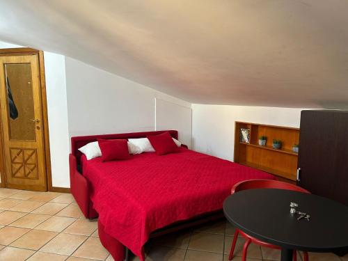 Schlafzimmer mit einem roten Bett und einem Tisch in der Unterkunft Frascati Roof 2 in Frascati