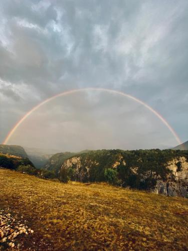 a rainbow in the sky over a field at Eco Lodge Eagle's Nest in Šavnik
