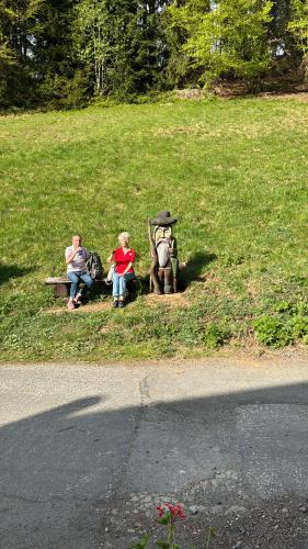 a group of three people sitting on a park bench at Penzion chalupa Lesní zátiší in Harrachov