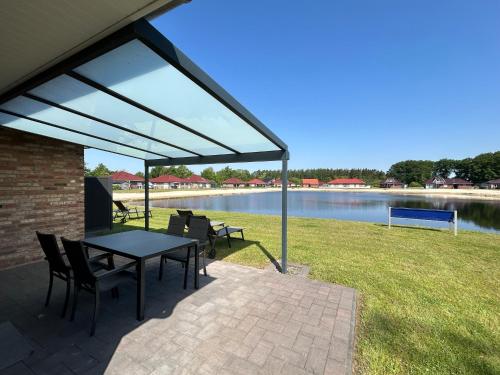 a patio with a table and chairs next to a lake at Seeufer in Walchum