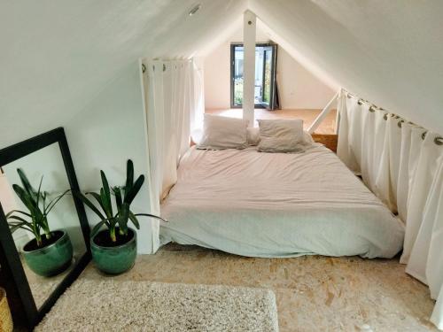 une chambre avec un lit avec des rideaux blancs et des plantes dans l'établissement MAISON ATYPIQUE EN BOIS 2 NIVEAUX 7,5km du circuit 24h, au Mans