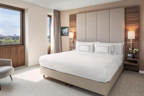 a bedroom with a large white bed and a window at Meliá Düsseldorf in Düsseldorf