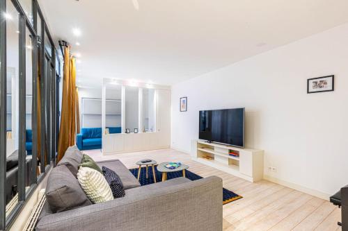 un salon avec un canapé et une télévision à écran plat dans l'établissement GuestReady - Modern stay near Place de la Bastille, à Paris
