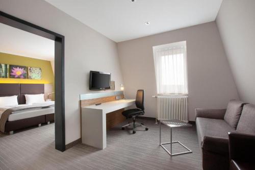 a hotel room with a bed and a desk with a computer at Willow Hotel Restaurant in Kötschlitz