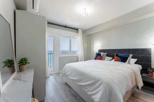 een witte slaapkamer met een groot bed en een raam bij MalagaSuite Golden Views Fuengirola in Fuengirola