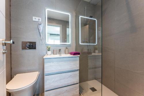 een badkamer met een toilet, een wastafel en een spiegel bij MalagaSuite Golden Views Fuengirola in Fuengirola