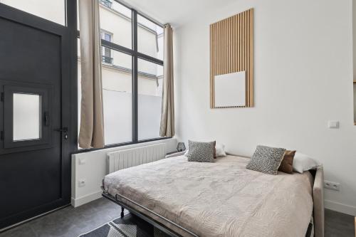 une chambre avec un lit et une grande fenêtre dans l'établissement Studio de Charme au Cœur de Paris!, à Paris