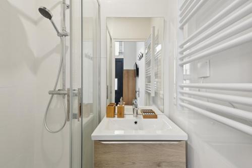 une salle de bain blanche avec un lavabo et un miroir dans l'établissement Studio de Charme au Cœur de Paris!, à Paris