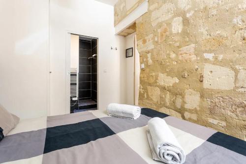 1 dormitorio con cama y pared de piedra en Lurbe Bleue - Bordeaux central et calme en Burdeos