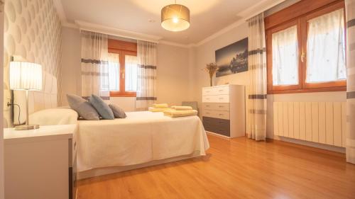 a bedroom with a white bed with a dresser and windows at Villa Luis R in Cájar