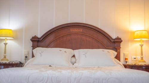 a bed with a wooden headboard and two lamps at Villa Luis R in Cájar