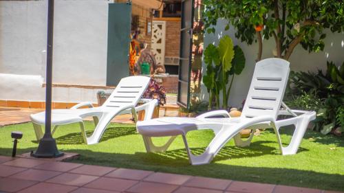 three white lawn chairs sitting on the grass at Villa Luis R in Cájar