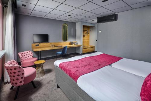 a hotel room with a bed and a desk and chairs at Hotel Restaurant Grandcafé 't Voorhuys in Emmeloord
