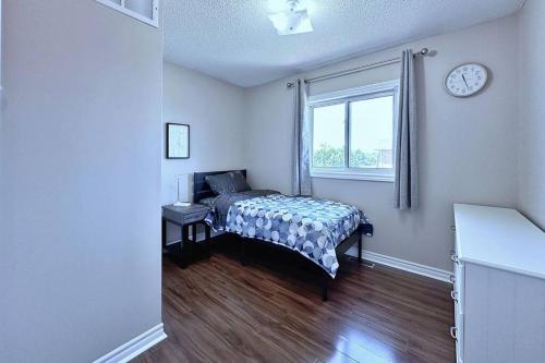 a bedroom with a bed and a window with a clock at Cozy house at south end Barrie in Barrie