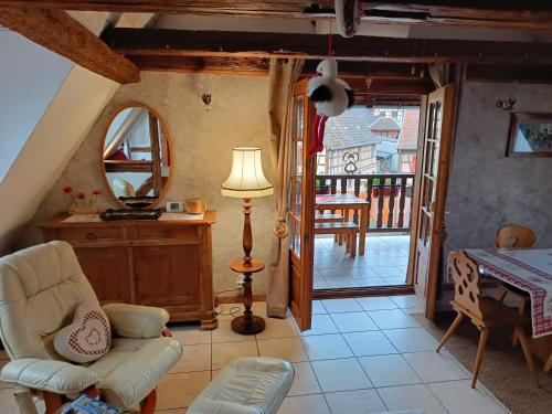 a living room with a chair and a table and a mirror at Un balcon sur les toits in Beblenheim