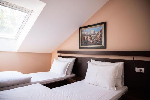a attic room with two beds and a window at Atrium in Sremska Mitrovica
