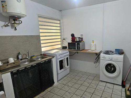 eine Küche mit einer Spüle und einer Waschmaschine in der Unterkunft JUNGLE HOUSE in Saint-Laurent du Maroni