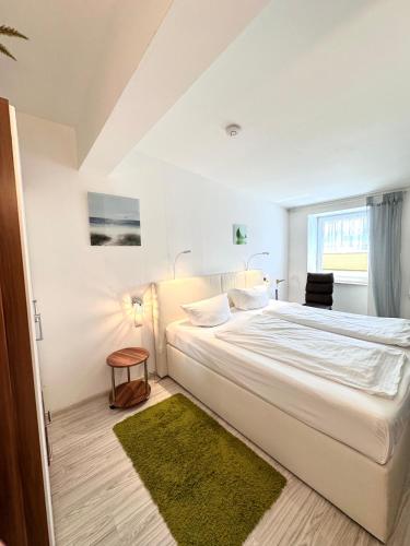 a white bedroom with a large bed with a green rug at Gästehaus Schulz in Ahlbeck