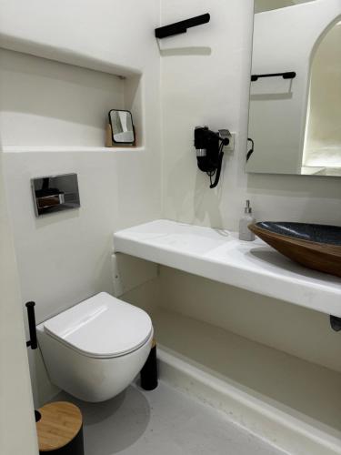 a white bathroom with a toilet and a sink at White Sand Jacuzzi Suite in Ios Chora