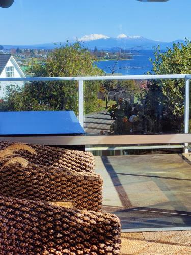 a balcony with a blue bench and a view of the ocean at Delight in Birch-Lake View Holiday Home in Taupo