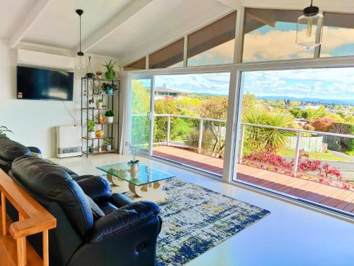 a living room with a leather couch and a large window at Delight in Birch-Lake View Holiday Home in Taupo