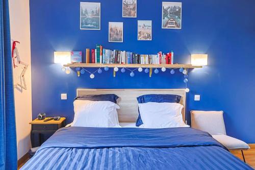 a blue bedroom with a bed and a shelf with books at Maison proche Disney in Chennevières-sur-Marne