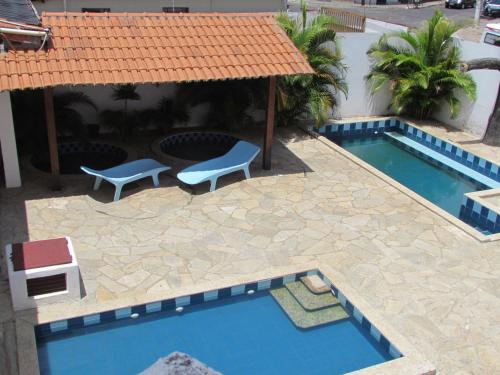 a pool with two chairs and a table next to a building at Hotel Imperador in Caldas Novas