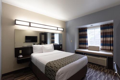 a hotel room with a large bed and a window at Microtel Inn & Suites by Wyndham Waynesburg in Waynesburg