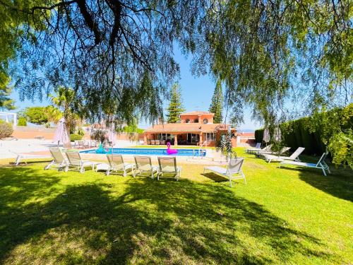 einen Garten mit Stühlen und einem Pool in der Unterkunft VILLA SOL Y LUNA Mediterránea in Alhaurín de la Torre