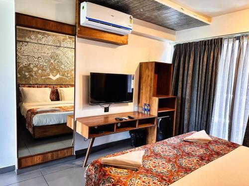 a hotel room with a bed and a desk with a television at Caravan Baga Aqua Resort in Baga
