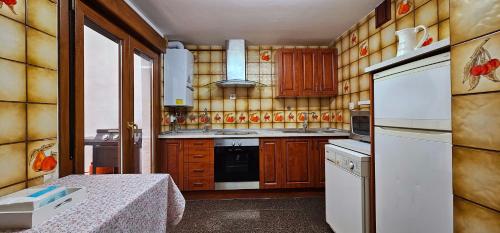 eine Küche mit Holzschränken und einem weißen Kühlschrank in der Unterkunft La Casa de Lorenzo in Laguardia