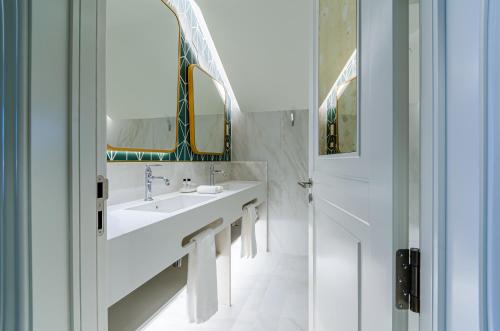a white bathroom with a sink and a mirror at The Emerald House Lisbon - Curio Collection By Hilton in Lisbon