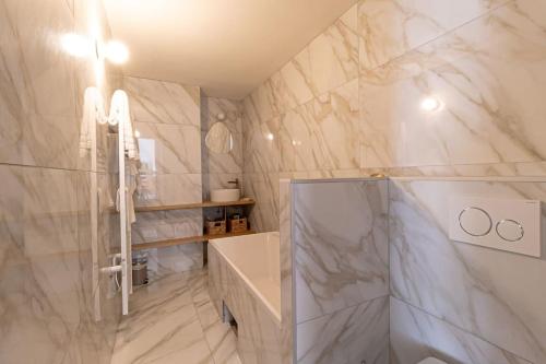 La salle de bains est pourvue de murs en marbre blanc et d'un lavabo. dans l'établissement La Restanque Cassis, à Cassis