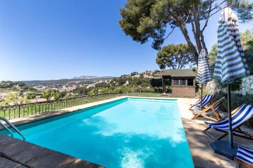 une piscine avec deux chaises et une maison dans l'établissement La Restanque Cassis, à Cassis