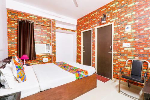 a bedroom with a bed and a brick wall at FabExpress The Hudco Grand in Patna