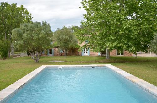- une piscine dans une cour avec des arbres et une maison dans l'établissement Bastide Des Oliviers, aux Arcs-sur-Argens