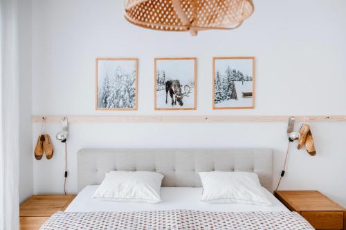 sypialnia z białym łóżkiem z czterema obrazami na ścianie w obiekcie Am Heimberg Skilift - Mullers x Kandahar Suite w mieście Parpan