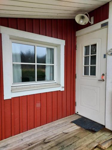 a red house with a white door and a window at Älgbergets Bed & Breakfast in Ucklum