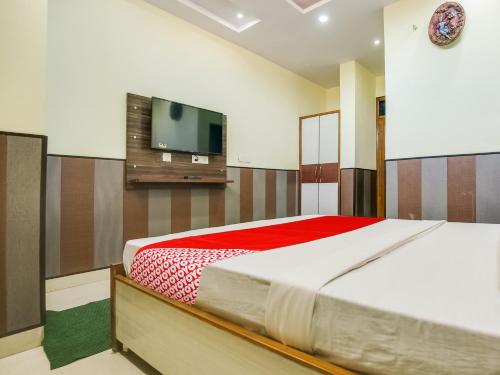 OYO Hotel HHH في شانديغار: غرفة نوم بسرير وتلفزيون بشاشة مسطحة