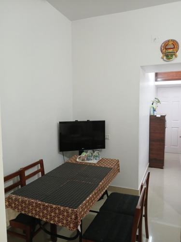 uma mesa com cadeiras e uma televisão num quarto em annies inn homestay em Cochin