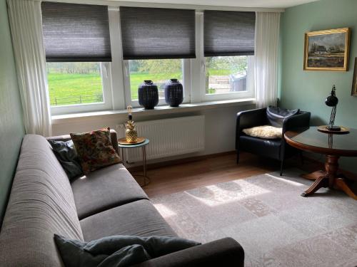 a living room with a couch and two chairs and windows at Ferienwohnung am Thalenbusch in Westerstede