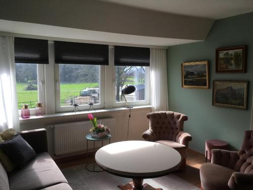 a living room with a table and chairs and windows at Ferienwohnung am Thalenbusch in Westerstede