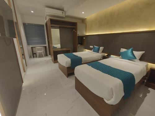a hotel room with two beds and a bathroom at Hotel La Premier in Hyderabad