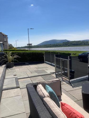 a couch sitting on a patio next to a body of water at Riverside Retreat in Dumfries in Dumfries