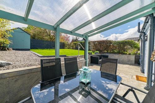 a covered patio with a glass table and chairs at Riverside Retreat in Dumfries in Dumfries